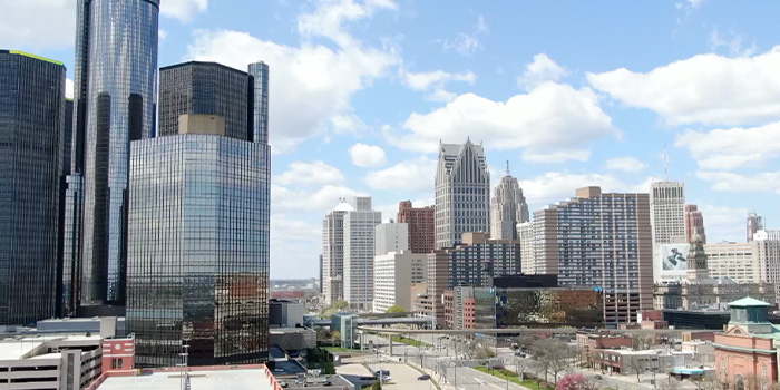 Downtown Detroit skyline with Renaissance Center glass towers, mixed historic and modern buildings under blue sky