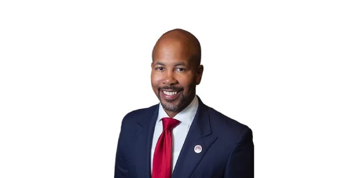 Smiling professional man executive headshot in navy suit and red tie on white background