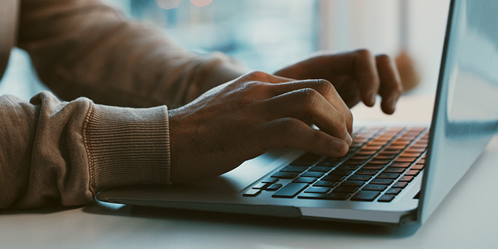 Close-up of a person typing on a laptop keyboard in a modern workspace