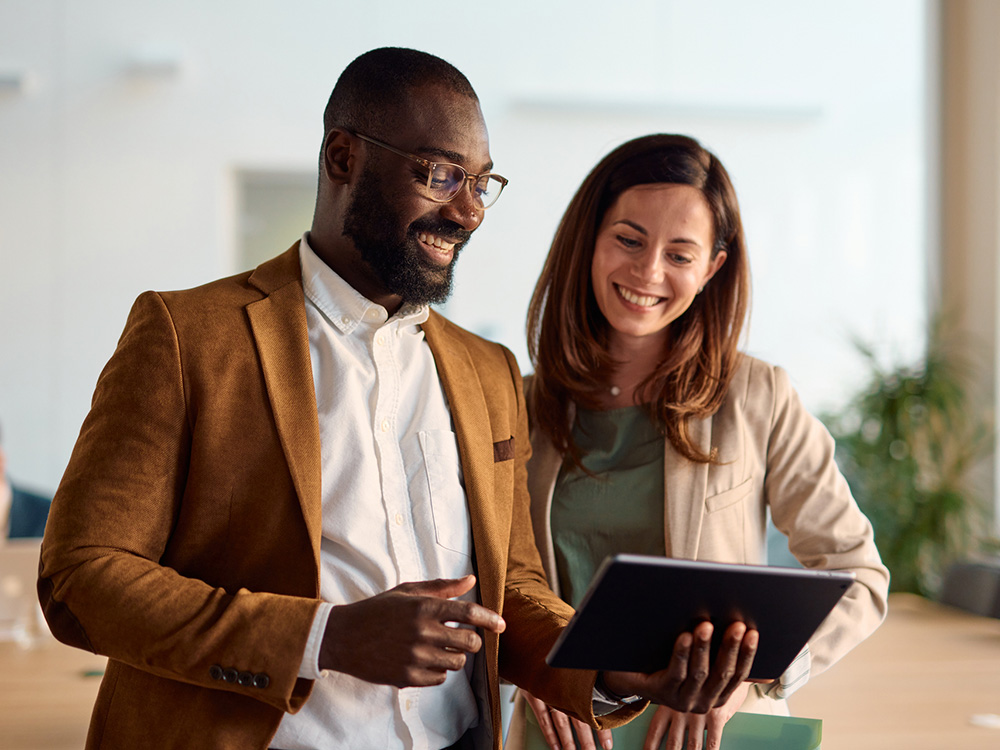 Business colleagues collaborating: a man and a woman reviewing a tablet in a bright modern office